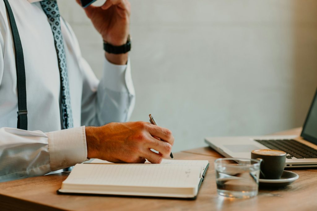 Cropped shot of a man having a meeting over the phone while writing down notes